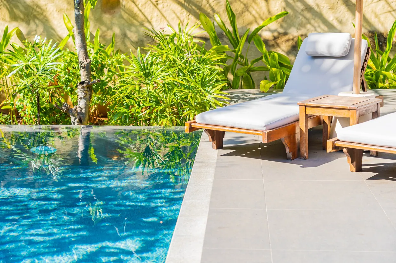 Pool loungers beneath palms