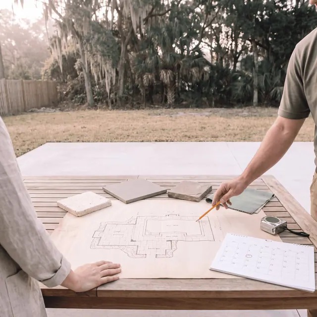 Hardscape layout drawings with travertine and paver samples on a table